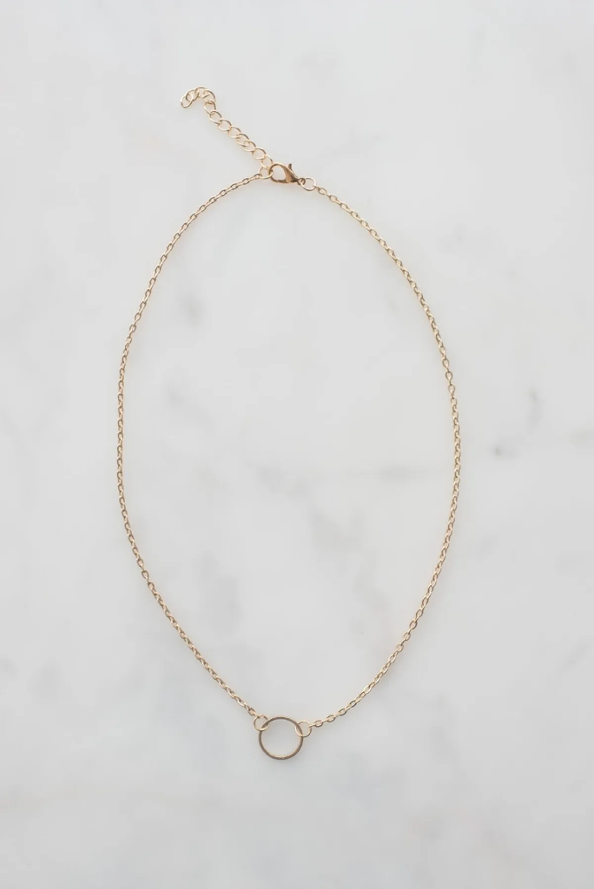 Chaine doree a pendentif circulaire posee a plat